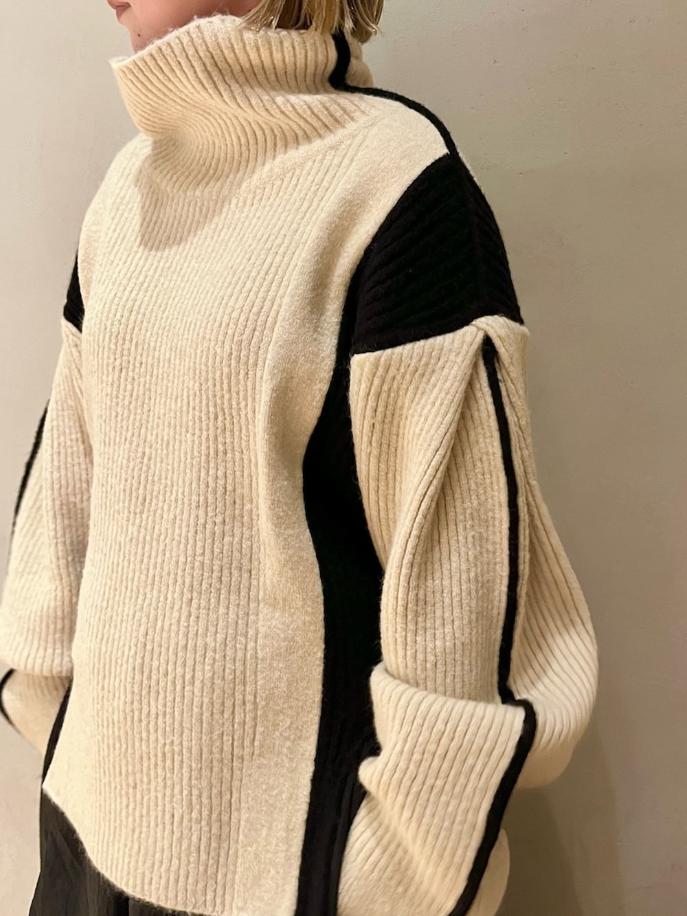 ブラック系のスカート、ホワイト系のニット/セーター、ブラック系のブーツを着用したレディースの秋コーディネートの7枚目の写真