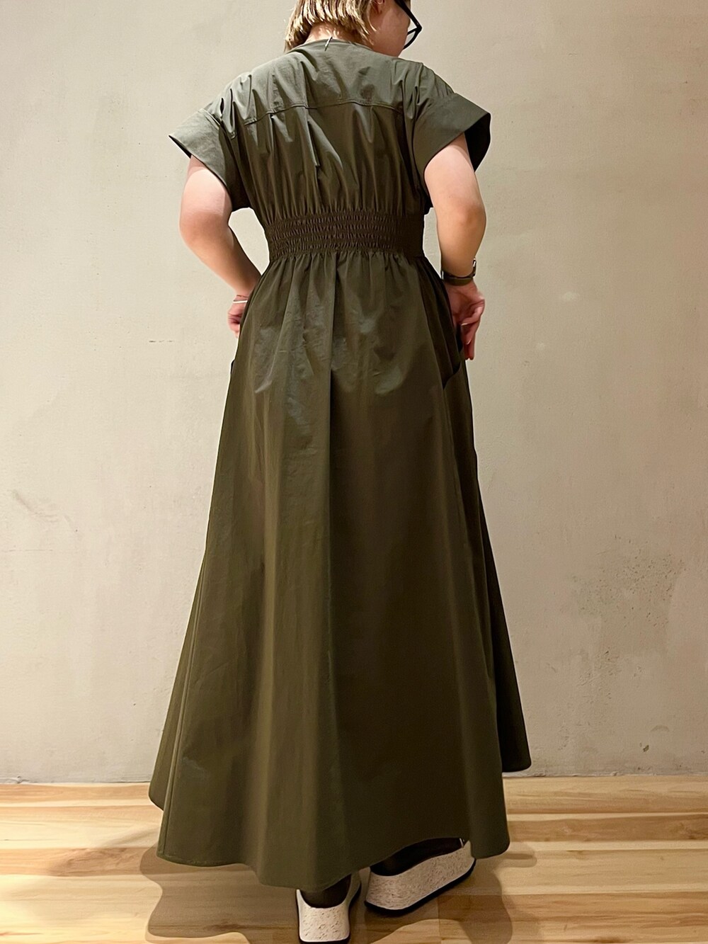 グリーン系のワンピース、ブラック系のスニーカー、シルバー系のネックレスを着用したレディースの冬コーディネートの3枚目の写真