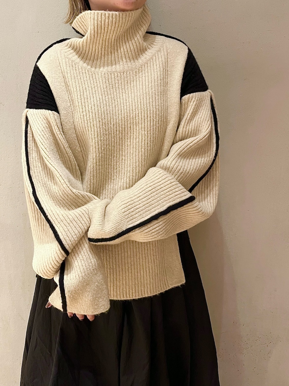 ブラック系のスカート、ホワイト系のニット/セーター、ブラック系のブーツを着用したレディースの秋コーディネートの4枚目の写真