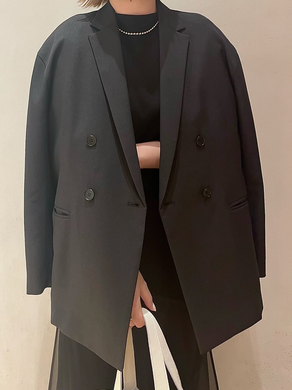 ブラック系のテーラードジャケット、ブラック系のワンピース、シルバー系のネックレスを着用したレディースの冬コーディネートの4枚目の写真