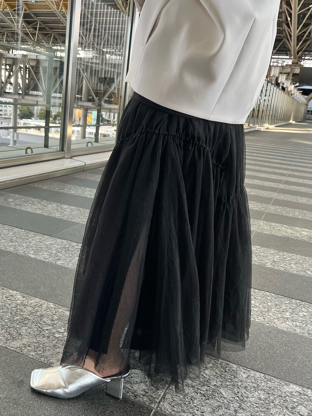 ベージュ系のノーカラーコート、ブラック系のタンクトップ、ブラック系のスカートを着用したレディースの冬コーディネートの9枚目の写真