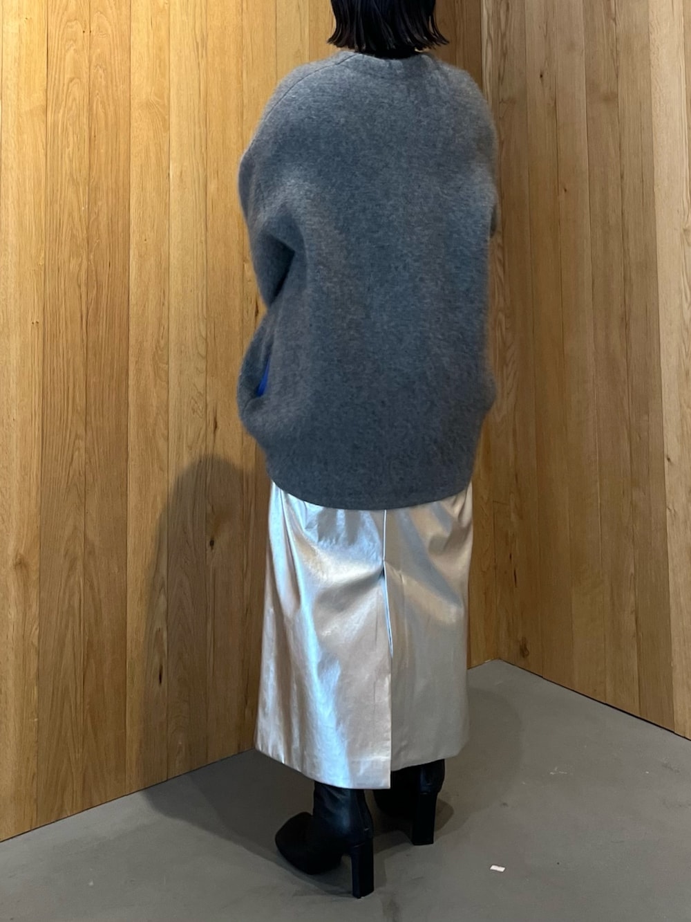 グレー系のカーディガン/ボレロ、シルバー系のスカート、ブラック系のブーツを着用したレディースの秋コーディネートの3枚目の写真