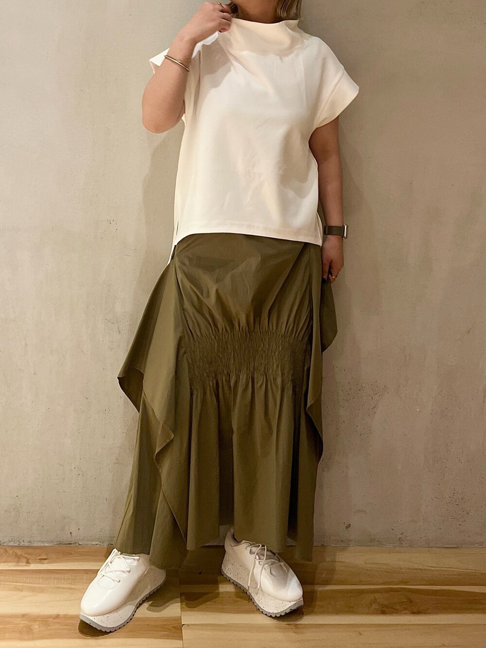 グリーン系のスカート、ホワイト系のTシャツ/カットソー、ホワイト系のスニーカーを着用したレディースの夏コーディネートの2枚目の写真
