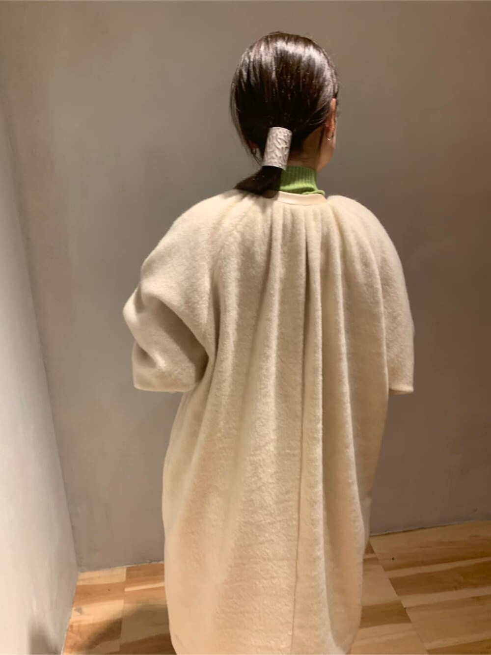 ブラック系のスカート、グリーン系のニット/セーター、ベージュ系のノーカラーコートを着用したレディースの秋コーディネートの3枚目の写真