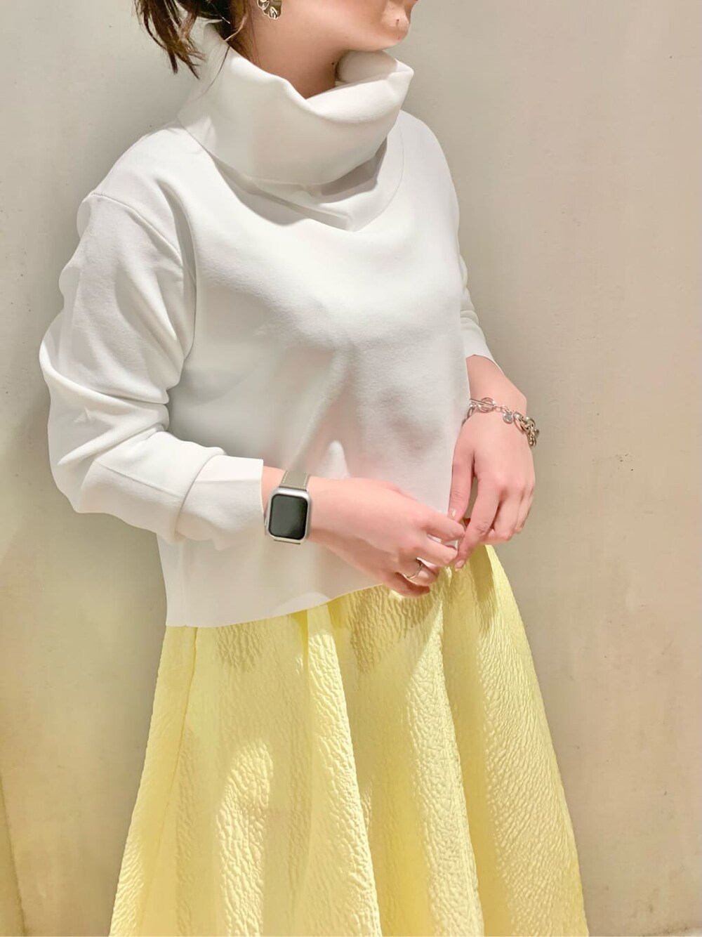 イエロー系のスカート、ホワイト系のニット/セーターを着用したレディースの冬コーディネートの4枚目の写真