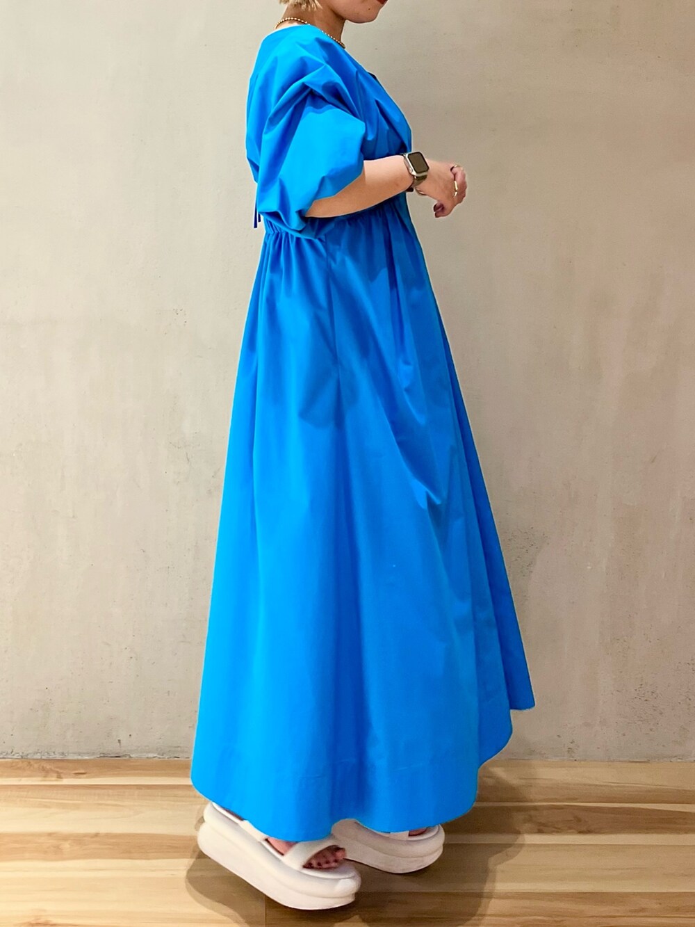 ブルー系のワンピース、ホワイト系のサンダル、ゴールド系のネックレスを着用したレディースの冬コーディネートの2枚目の写真