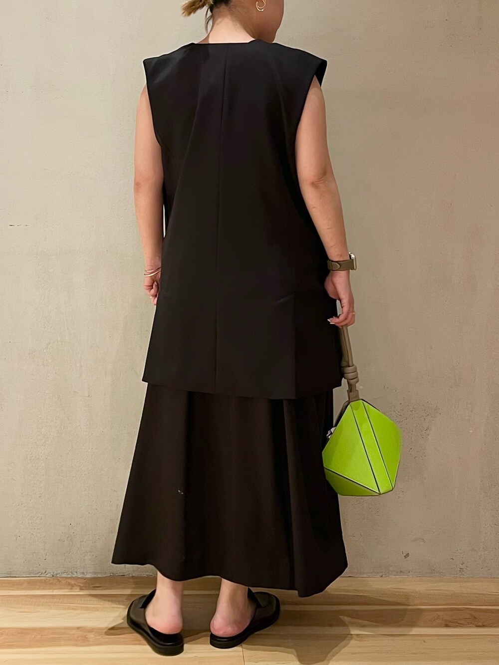 ブラック系のテーラードジャケット、ブラック系のワンピース、グリーン系のハンドバッグを着用したレディースの冬コーディネートの2枚目の写真