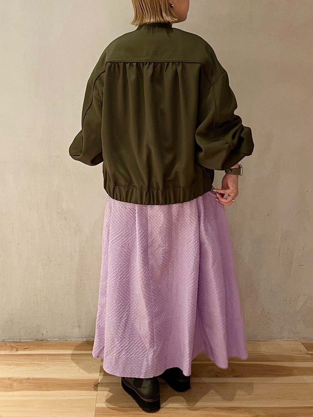 グリーン系のブルゾン、パープル系のワンピースを着用したレディースの春コーディネートの3枚目の写真