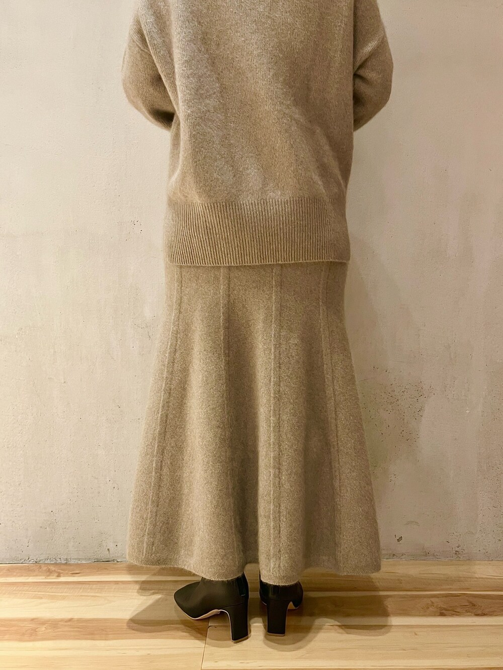 ベージュ系のニット/セーター、ベージュ系のスカート、ブラック系のブーツを着用したレディースの秋コーディネートの8枚目の写真