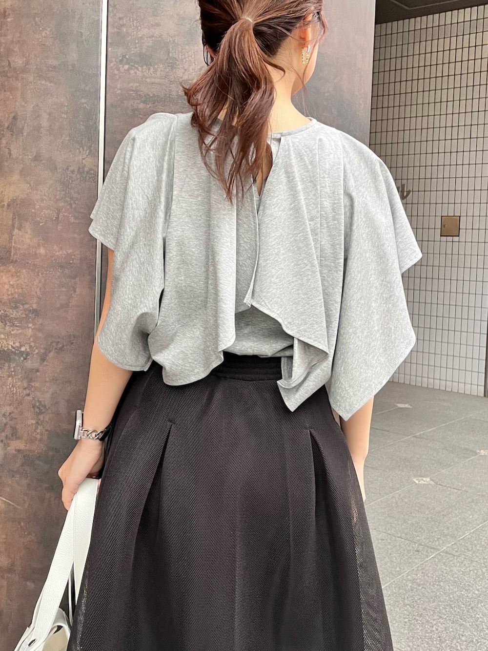 グレー系のTシャツ/カットソー、ブラック系のスカート、ブラック系のパンプスを着用したレディースの春コーディネートの5枚目の写真