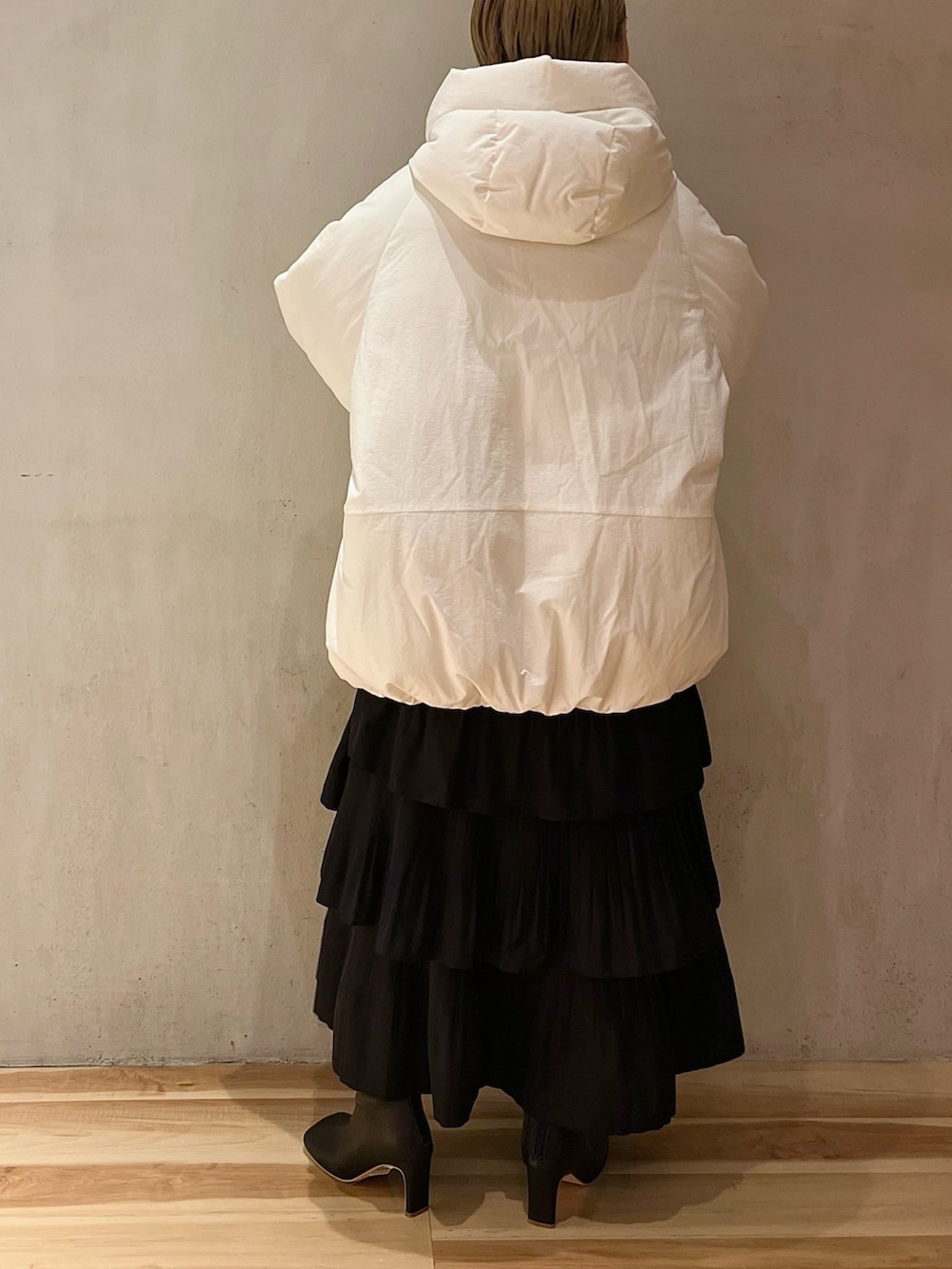 ホワイト系のダウンジャケット/コート、パープル系のニット/セーター、ブラック系のスカートを着用したレディースの夏コーディネートの3枚目の写真