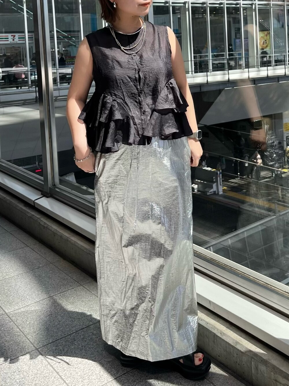 ブラック系のシャツ/ブラウス、シルバー系のスカート、ブラック系のサンダルを着用したレディースの春コーディネートの3枚目の写真