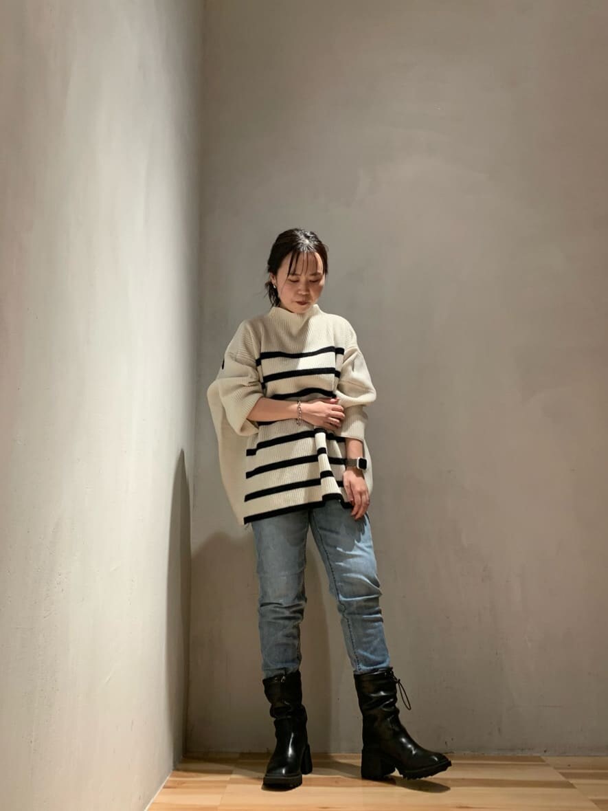 ブルー系のデニムパンツ、ブラック系のブーツ、ホワイト系のニット/セーターを着用したレディースの秋コーディネートの4枚目の写真