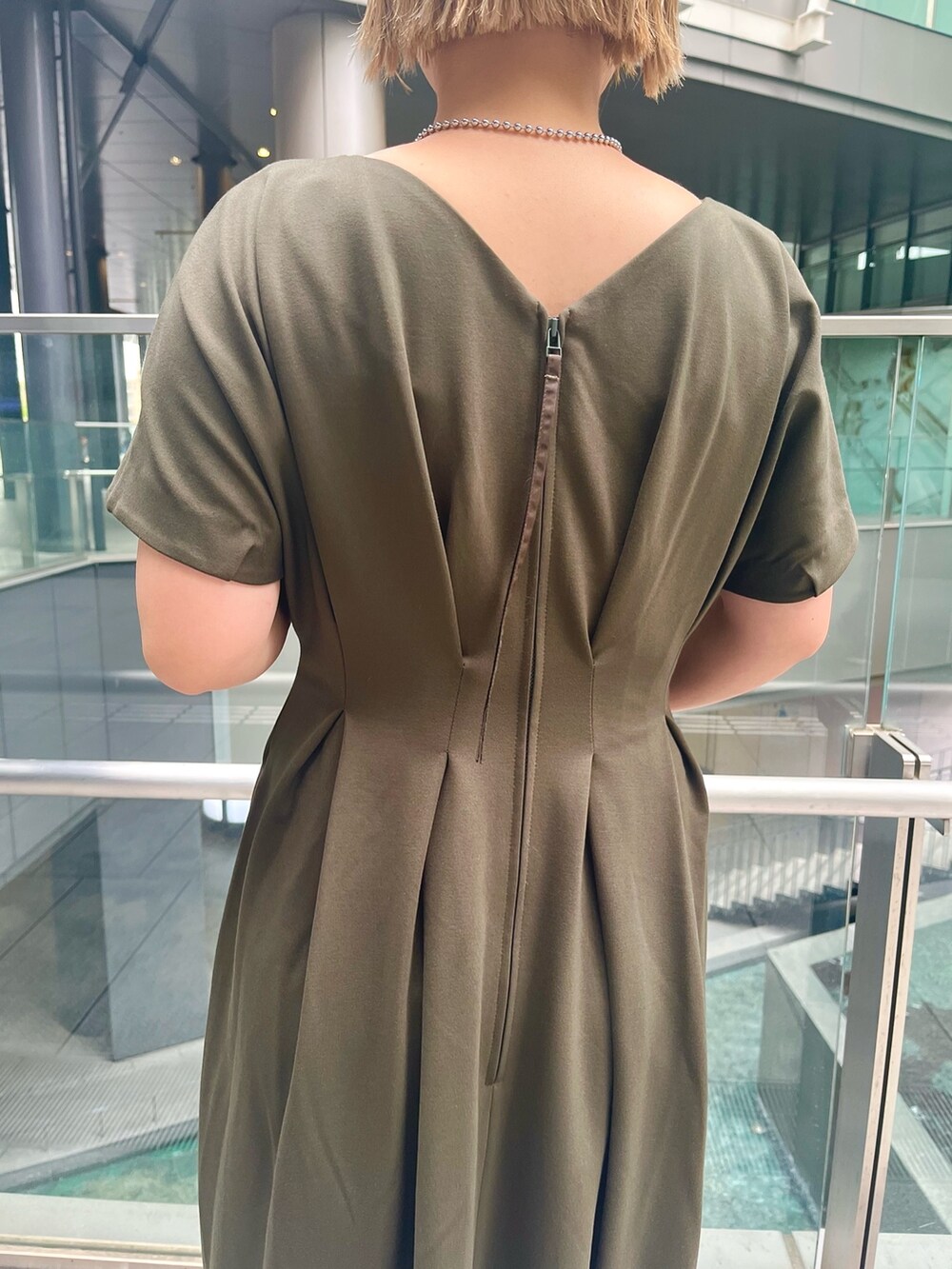 グリーン系のワンピース、ブラック系のブーツ、ブラック系のショルダーバッグを着用したレディースの春コーディネートの6枚目の写真