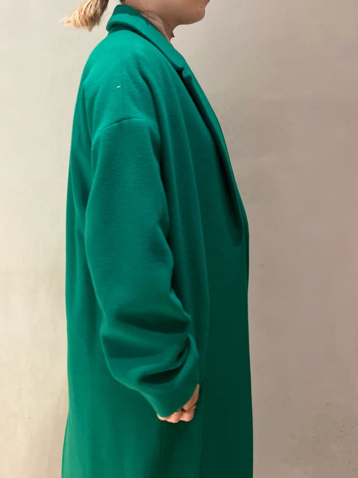 ブラック系のジャンパースカート、ブラウン系のニット/セーター、グリーン系のチェスターコートを着用したレディースの秋コーディネートの6枚目の写真