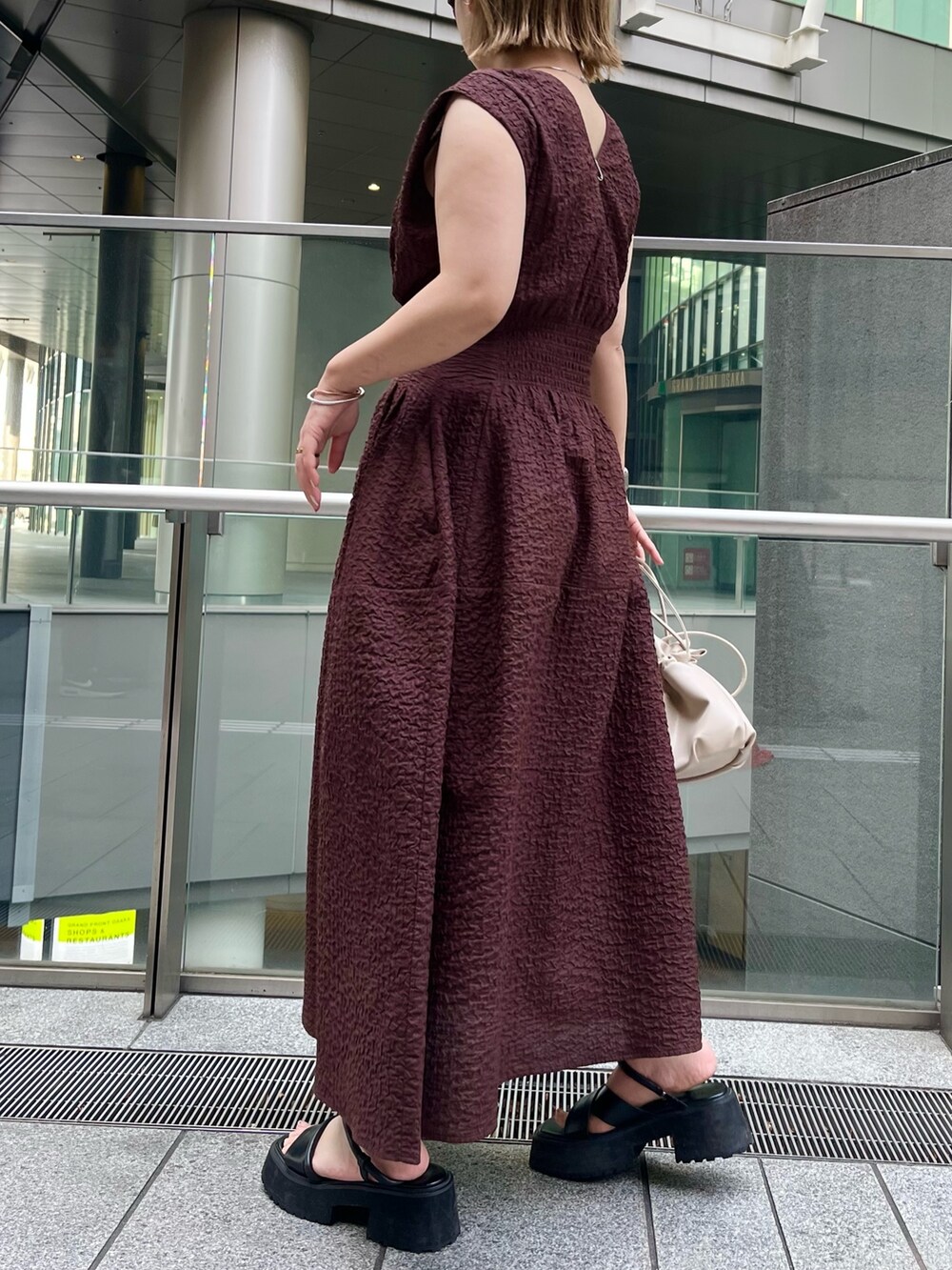 ブラック系のサンダル、ブラウン系のワンピース、シルバー系のネックレスを着用したレディースの冬コーディネートの2枚目の写真