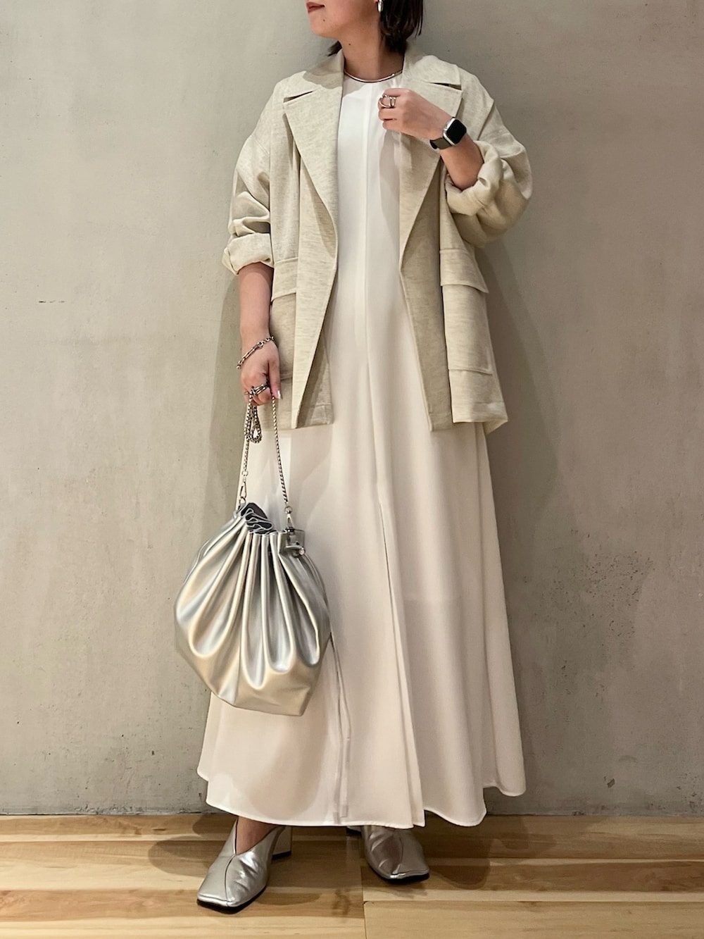 ベージュ系のテーラードジャケット、ホワイト系のワンピース、シルバー系のショルダーバッグを着用したレディースの春コーディネートの2枚目の写真