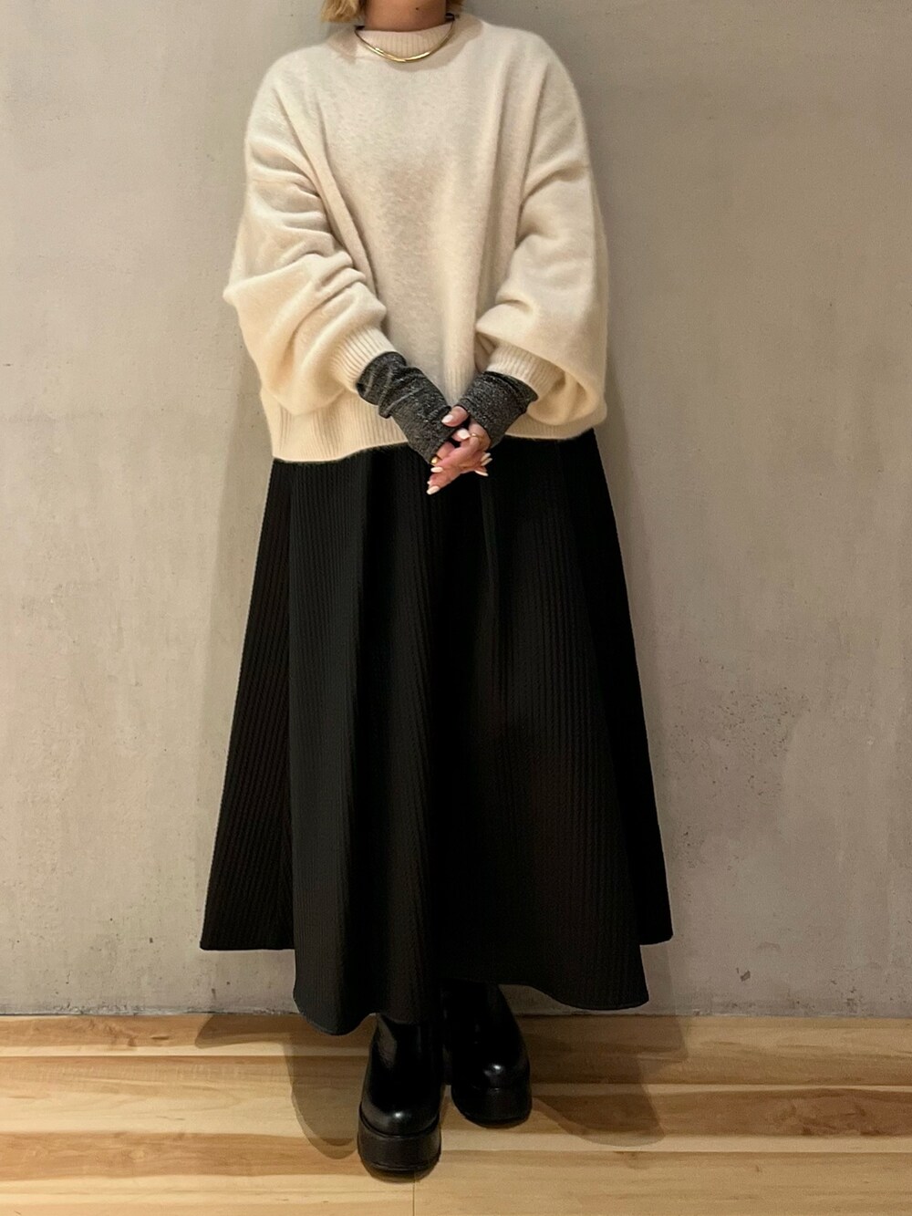 ホワイト系のニット/セーター、シルバー系のTシャツ/カットソー、ブラック系のスカートを着用したレディースの冬コーディネートの4枚目の写真