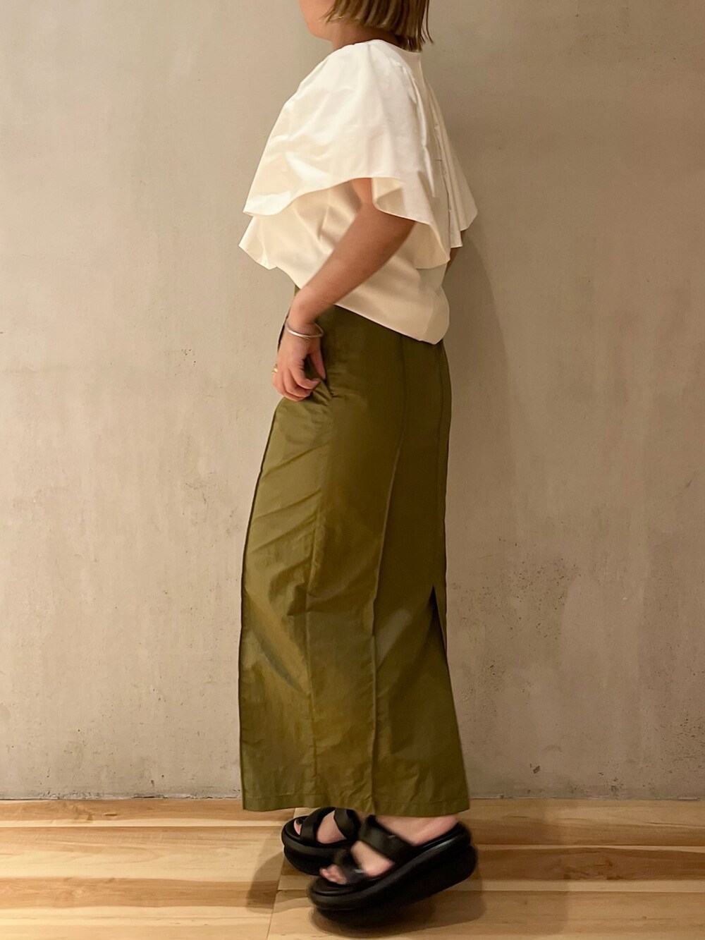 ホワイト系のTシャツ/カットソー、グリーン系のスカート、ブラック系のサンダルを着用したレディースの春コーディネートの2枚目の写真