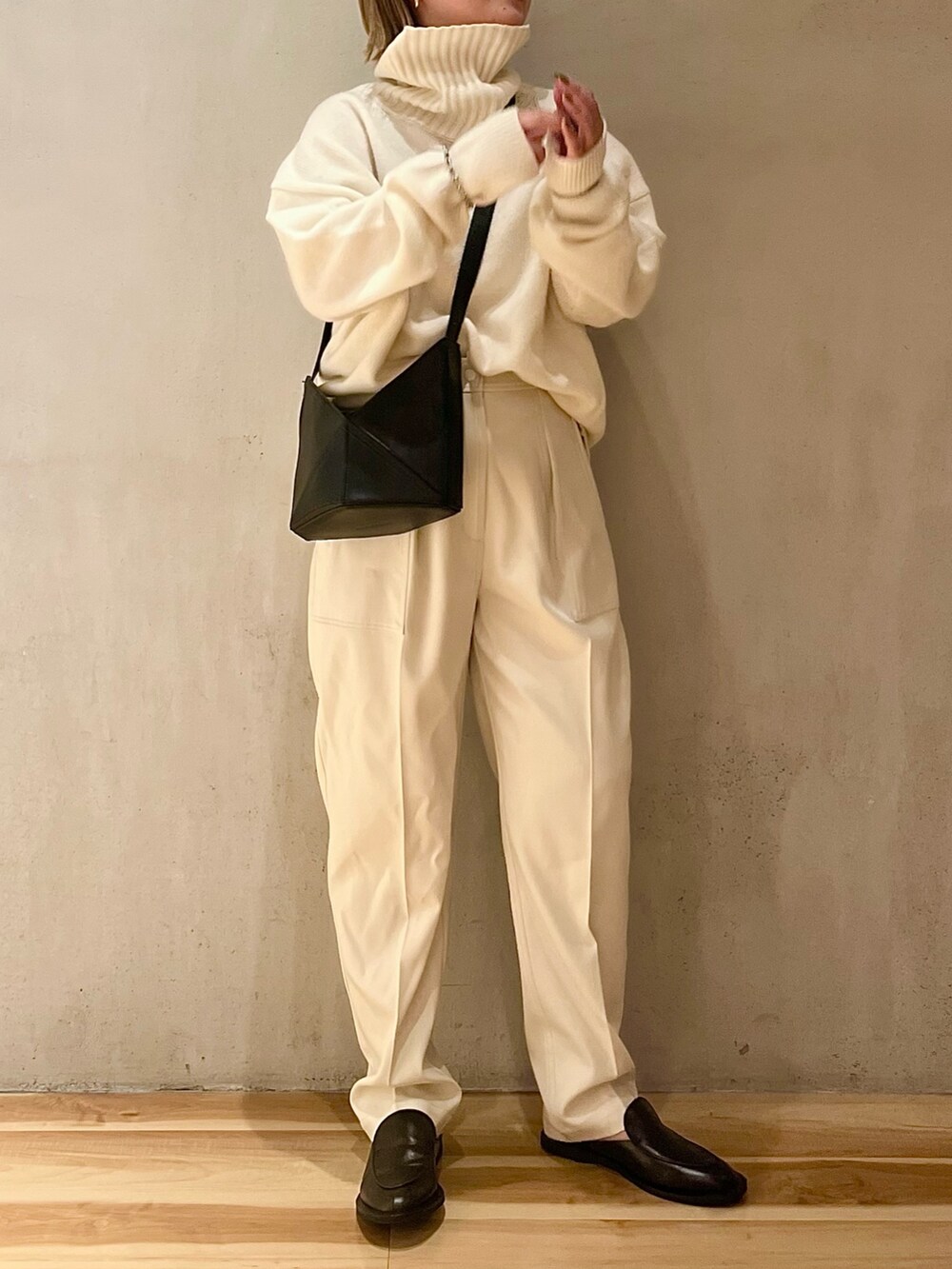 ホワイト系のニット/セーター、ホワイト系のその他パンツ、ブラック系のハンドバッグを着用したレディースの夏コーディネートの2枚目の写真