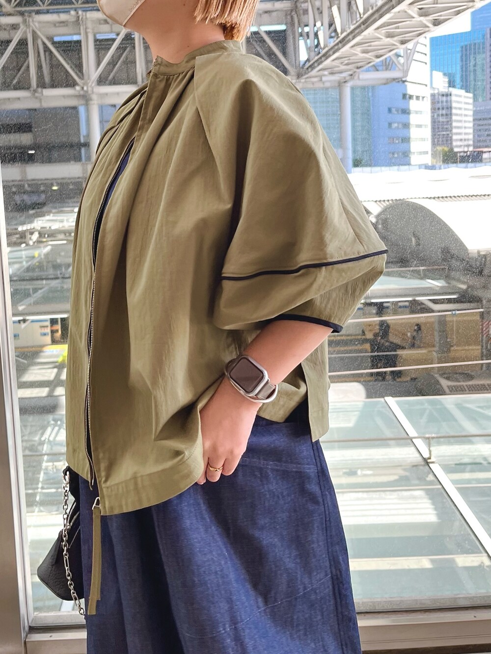 グリーン系のブルゾン、ブルー系のワンピース、ブラック系のスニーカーを着用したレディースの春コーディネートの4枚目の写真