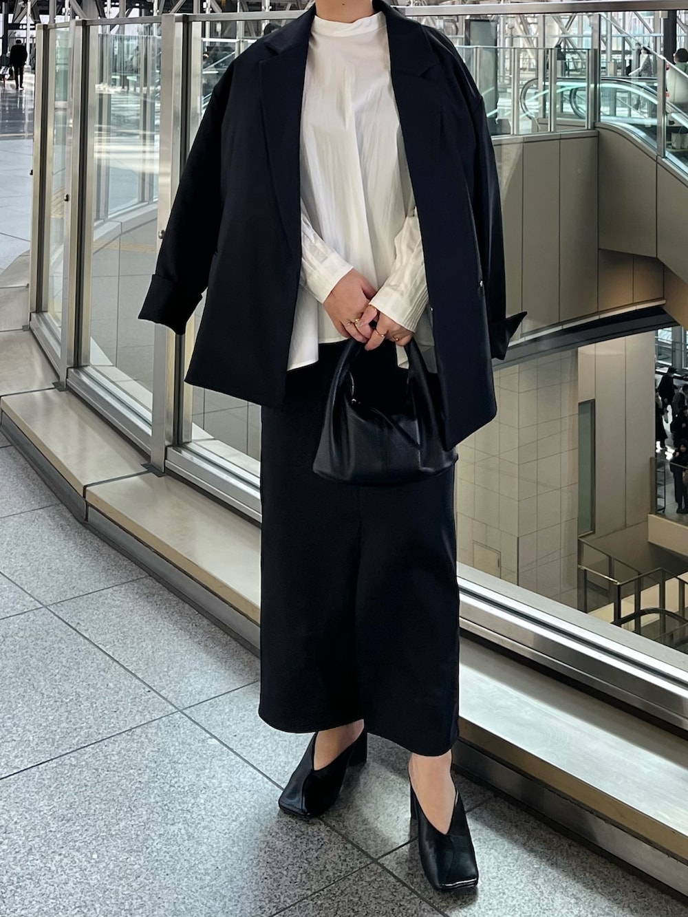 ブラック系のテーラードジャケット、ブラック系のスカート、ホワイト系のシャツ/ブラウスを着用したレディースの冬コーディネートの2枚目の写真