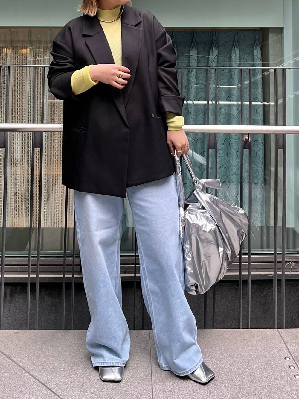 ブラック系のテーラードジャケット、イエロー系のニット/セーター、ブルー系のデニムパンツを着用したレディースの冬コーディネートの3枚目の写真