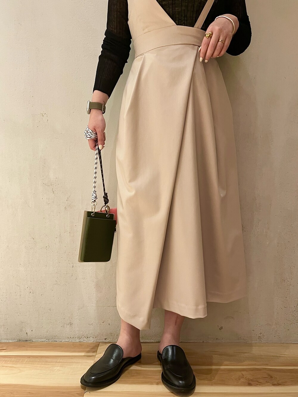 ベージュ系のショルダーバッグ、ベージュ系のジャンパースカート、ブラック系のニット/セーターを着用したレディースの冬コーディネートの6枚目の写真