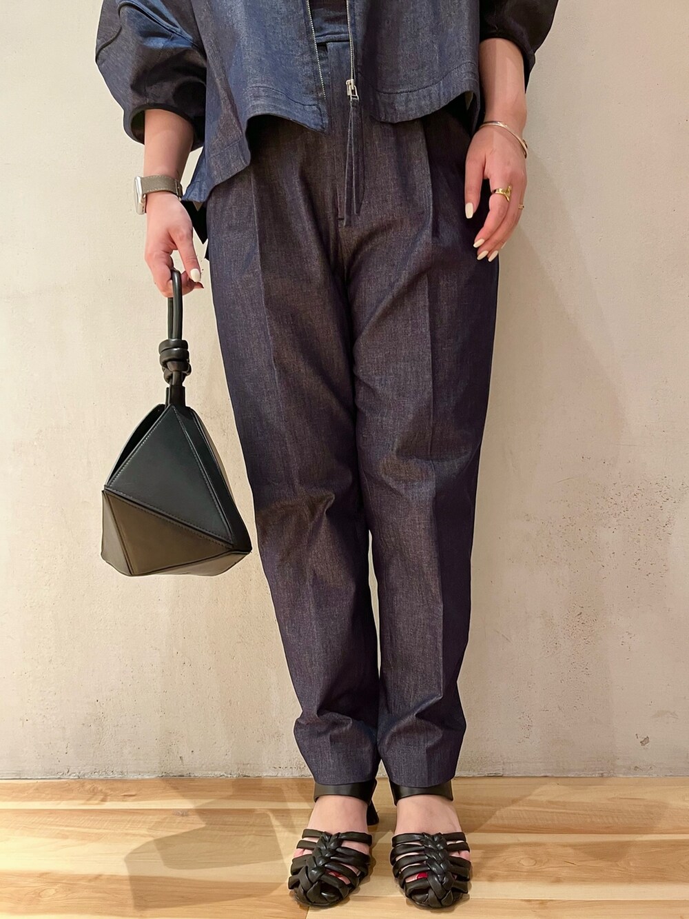 ブラック系のハンドバッグ、ブラック系のサンダル、ブルー系のブルゾンを着用したレディースの春コーディネートの7枚目の写真