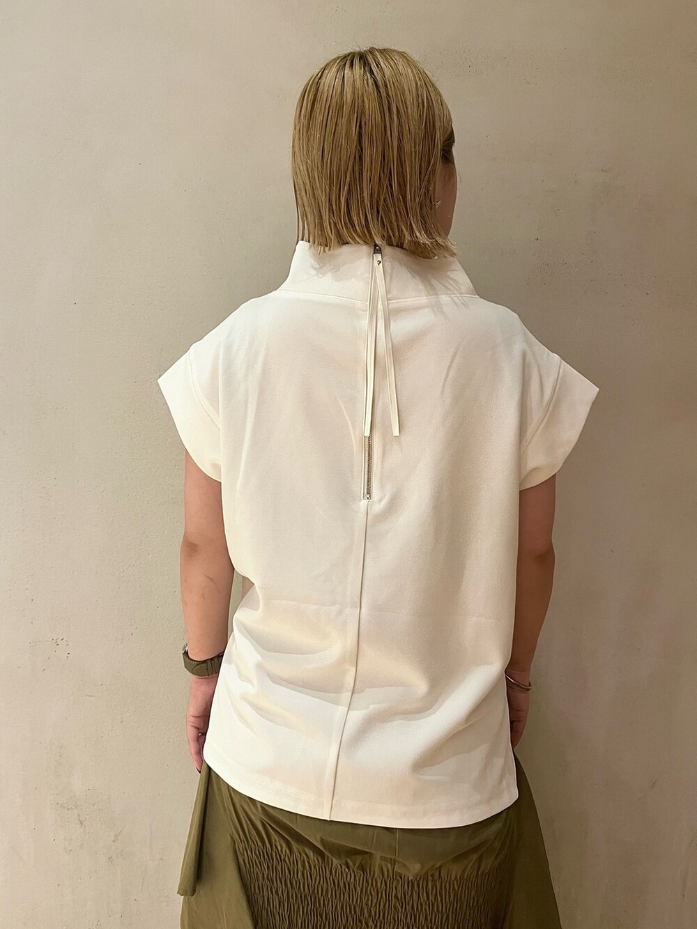 グリーン系のスカート、ホワイト系のTシャツ/カットソー、ホワイト系のスニーカーを着用したレディースの夏コーディネートの6枚目の写真