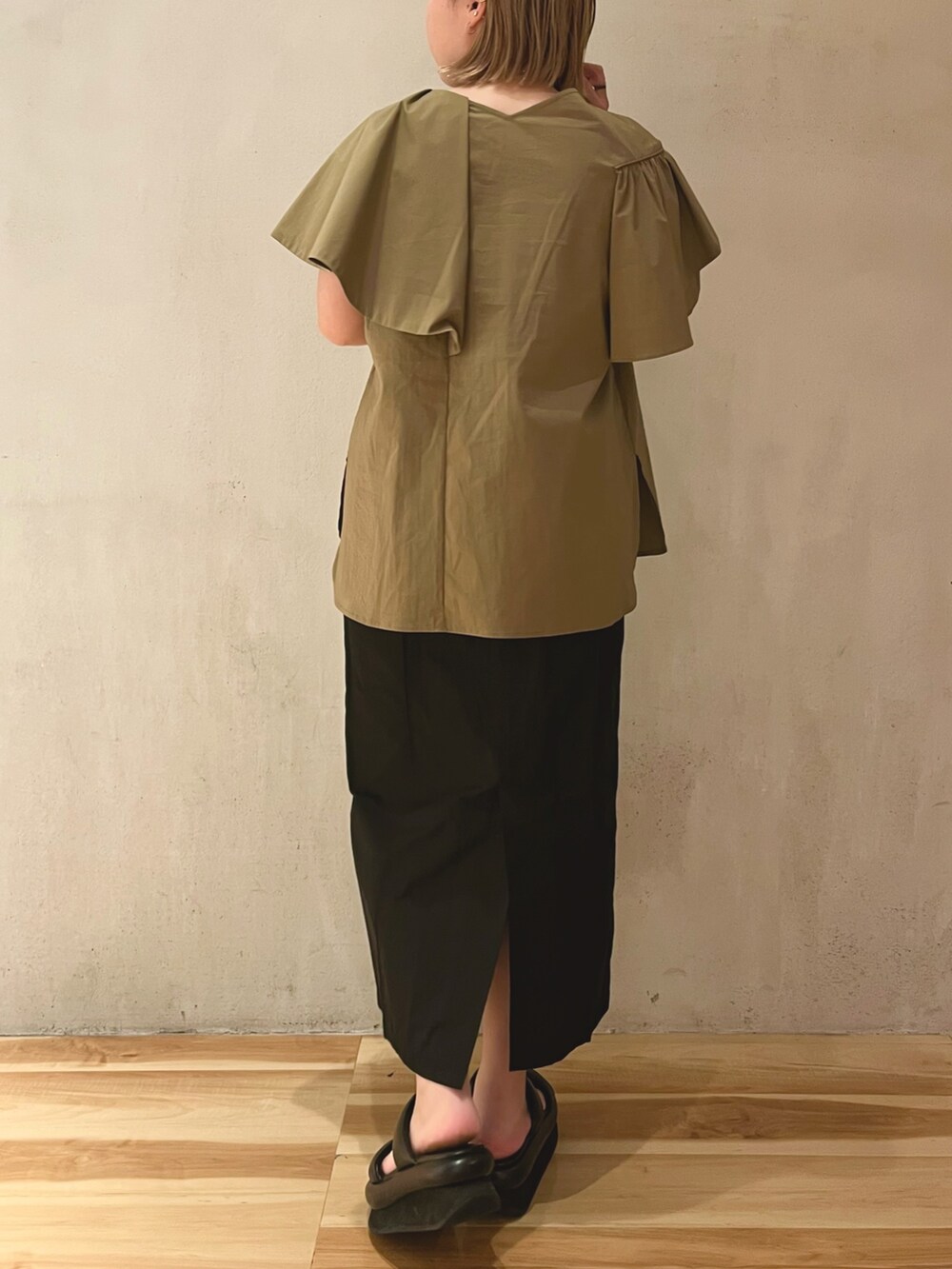 グリーン系のシャツ/ブラウス、ブラック系のスカート、ブラック系のサンダルを着用したレディースの冬コーディネートの3枚目の写真