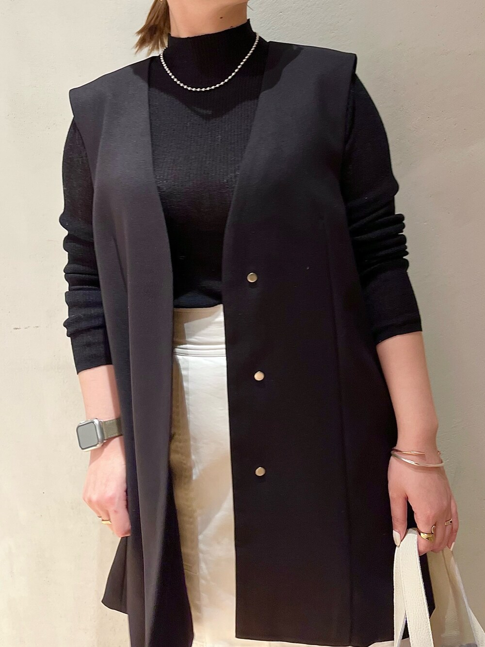 ホワイト系のスカート、ホワイト系のハンドバッグ、ブラック系のテーラードジャケットを着用したレディースの冬コーディネートの6枚目の写真