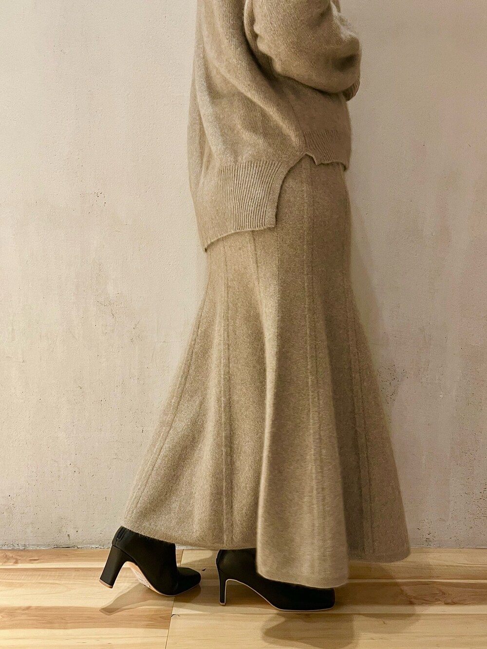 ベージュ系のニット/セーター、ベージュ系のスカート、ブラック系のブーツを着用したレディースの秋コーディネートの7枚目の写真