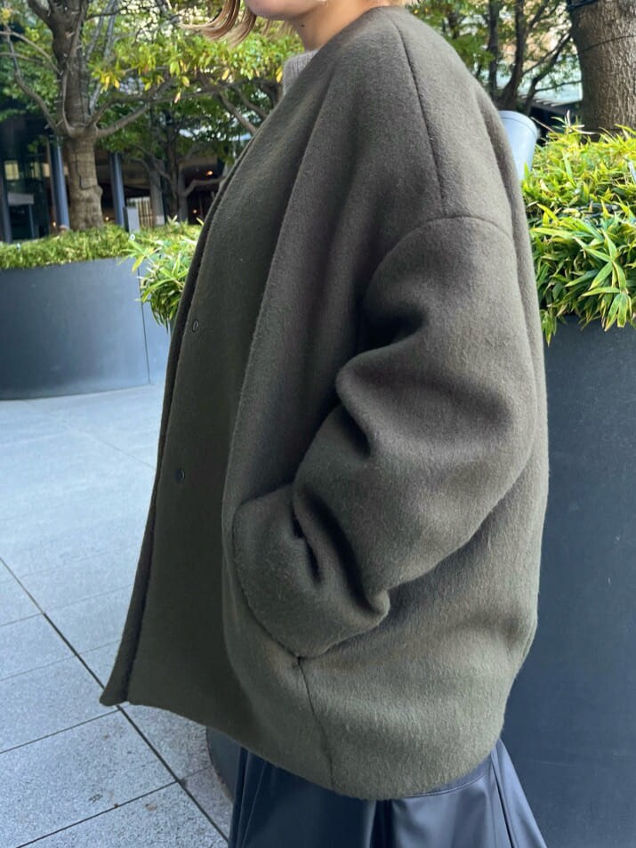 ブラック系のスカート、ブラック系のブーツ、グリーン系のノーカラーコートを着用したレディースの秋コーディネートの8枚目の写真