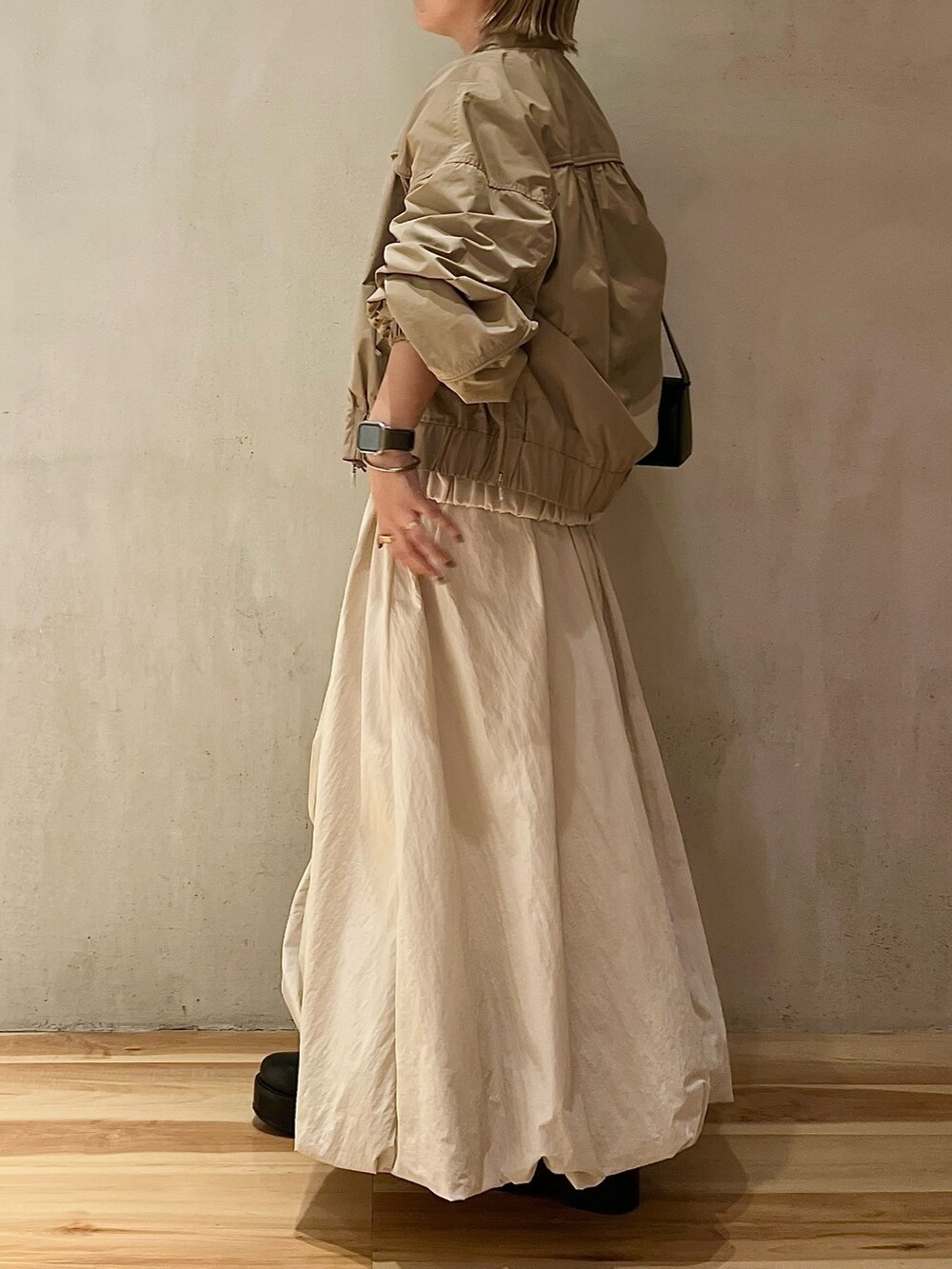 ベージュ系のブルゾン、ベージュ系のワンピース、ブラック系のブーツを着用したレディースの夏コーディネートの2枚目の写真