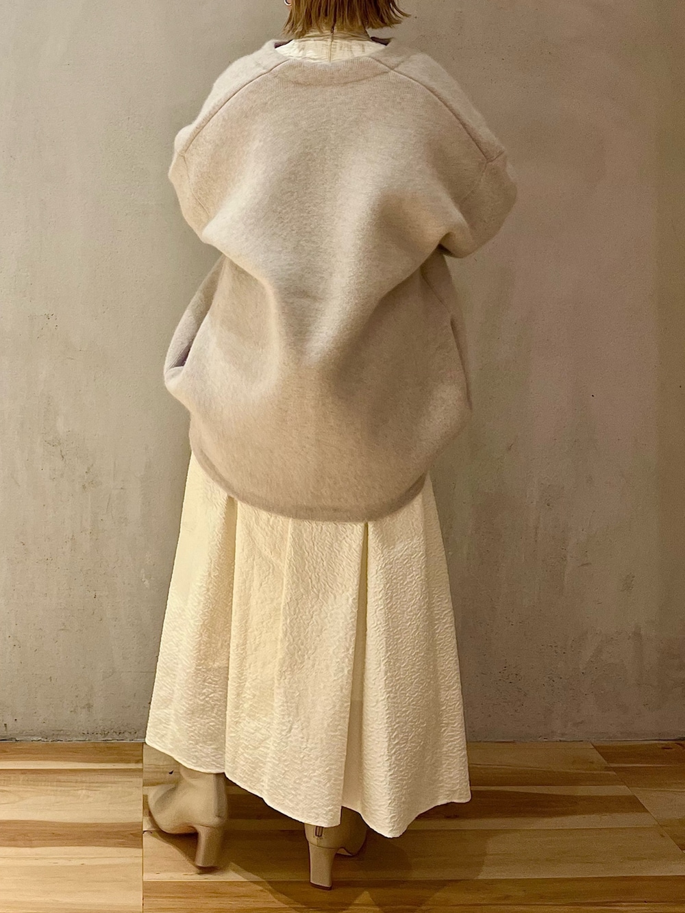 ホワイト系のノーカラージャケット、ホワイト系のワンピース、ベージュ系のブーツを着用したレディースの秋コーディネートの3枚目の写真