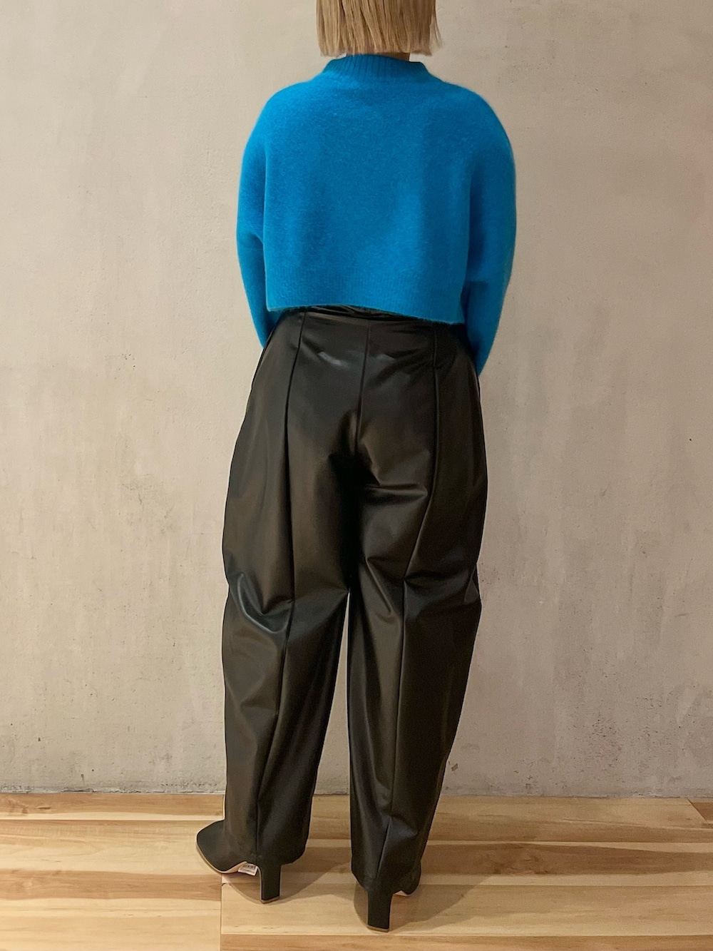 ブルー系のニット/セーター、ブラック系のその他パンツ、ブラック系のブーツを着用したレディースの秋コーディネートの4枚目の写真