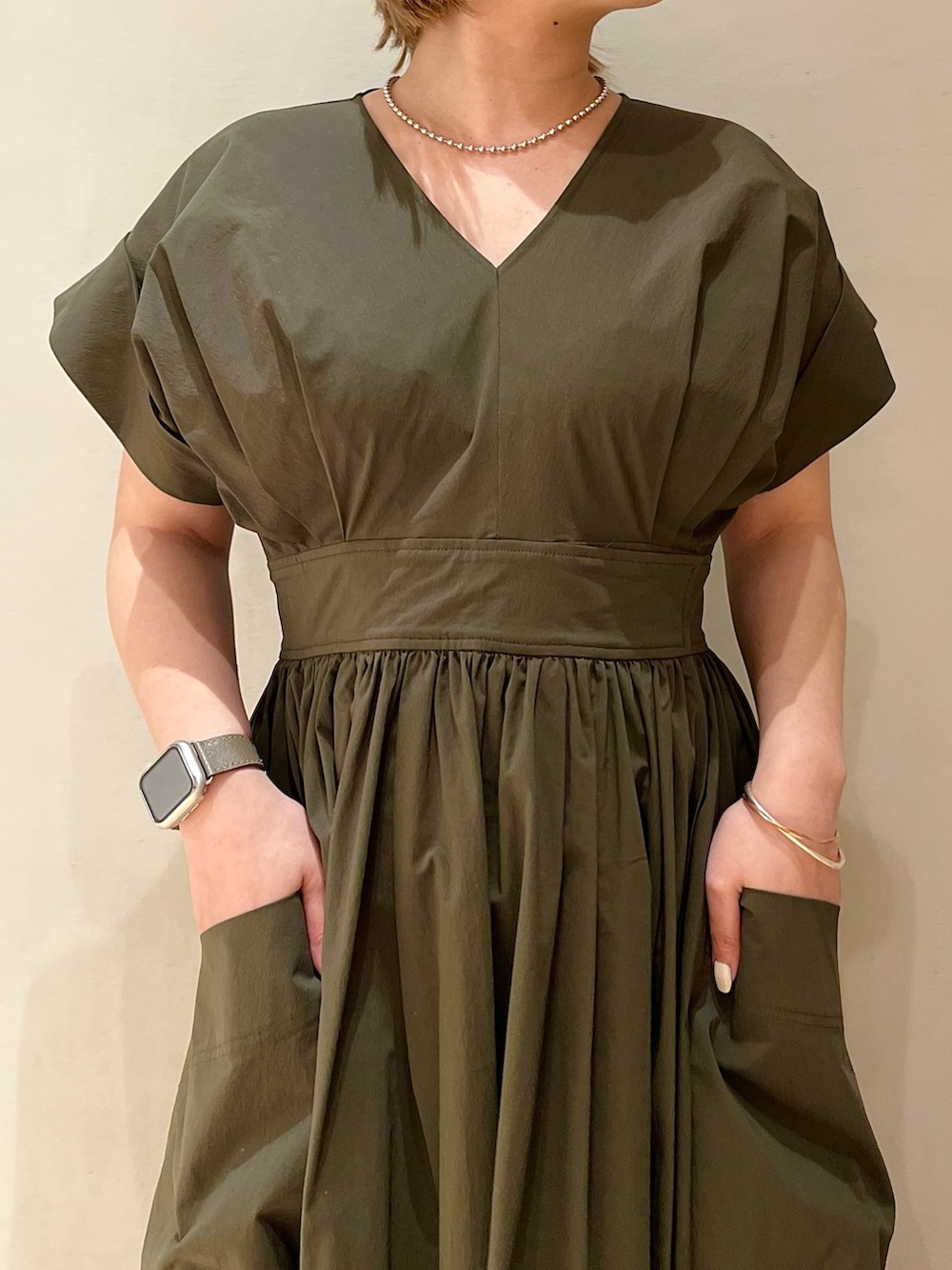 グリーン系のワンピース、ブラック系のスニーカー、シルバー系のネックレスを着用したレディースの冬コーディネートの5枚目の写真