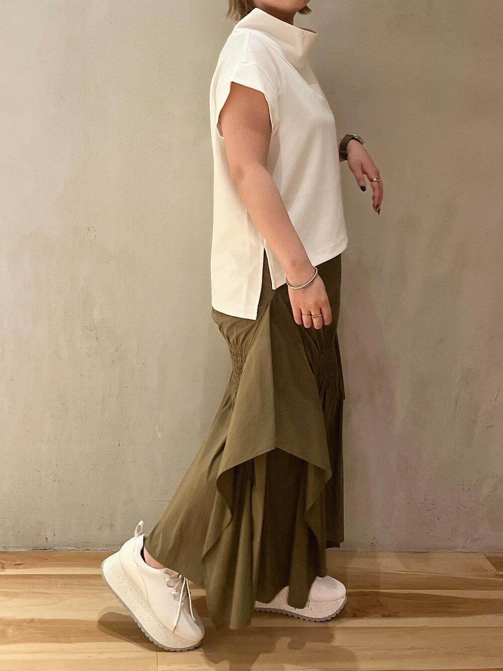 グリーン系のスカート、ホワイト系のTシャツ/カットソー、ホワイト系のスニーカーを着用したレディースの夏コーディネートの3枚目の写真