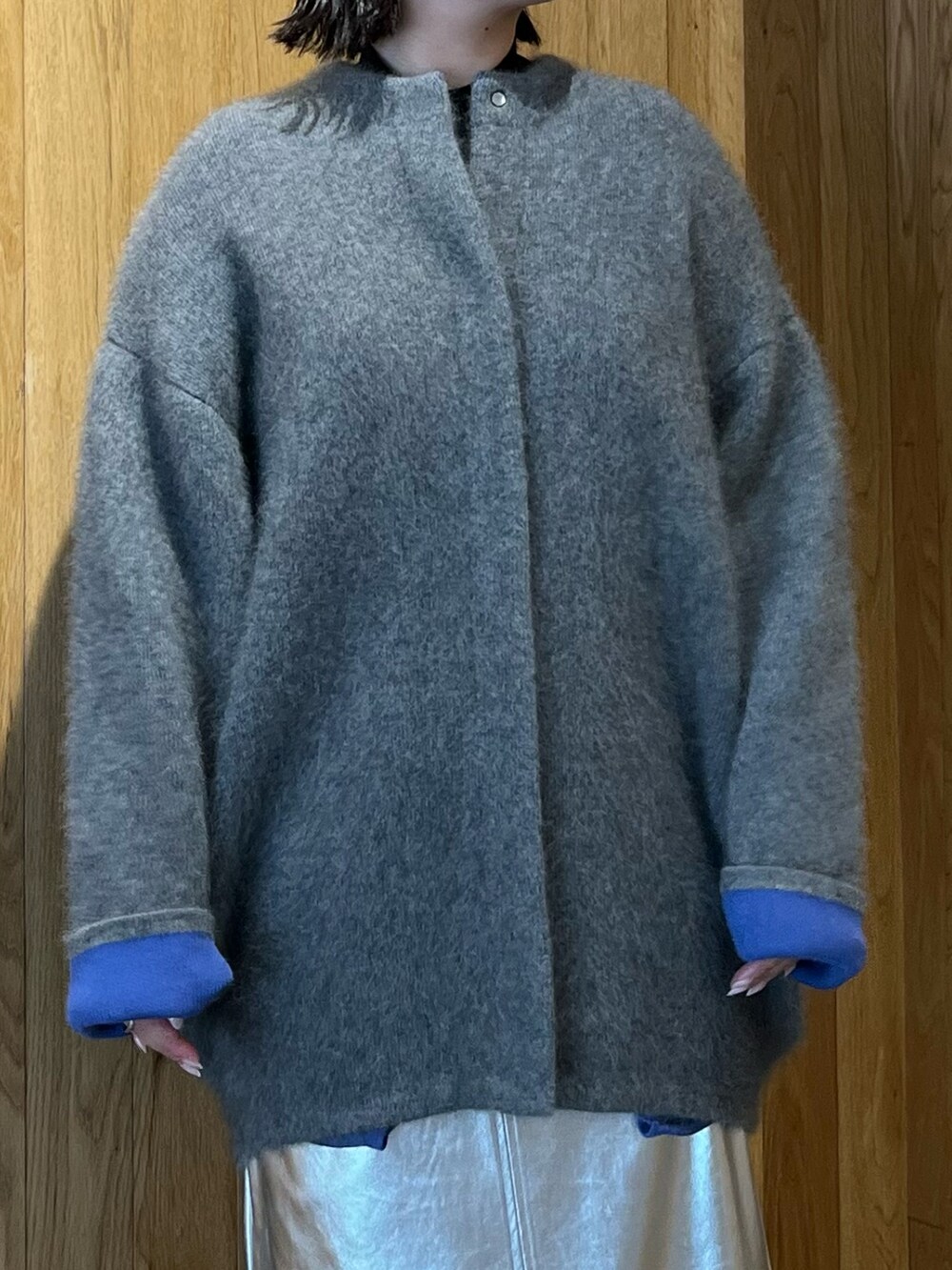 グレー系のカーディガン/ボレロ、シルバー系のスカート、ブラック系のブーツを着用したレディースの秋コーディネートの7枚目の写真