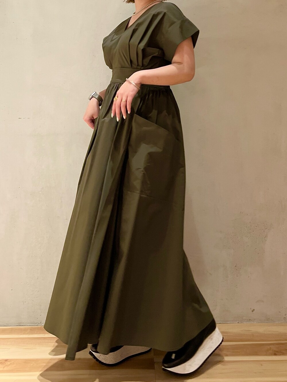 グリーン系のワンピース、ブラック系のスニーカー、シルバー系のネックレスを着用したレディースの冬コーディネートの2枚目の写真