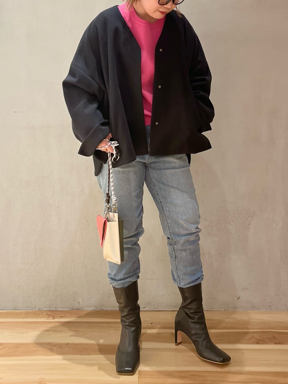 ピンク系のニット/セーター、ブラック系のステンカラーコート、ベージュ系のショルダーバッグを着用したレディースの冬コーディネートの2枚目の写真