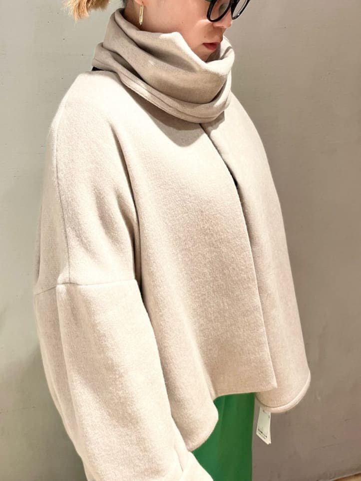 グリーン系のスカート、ベージュ系のノーカラーコート、ブラック系のニット/セーターを着用したレディースの秋コーディネートの5枚目の写真