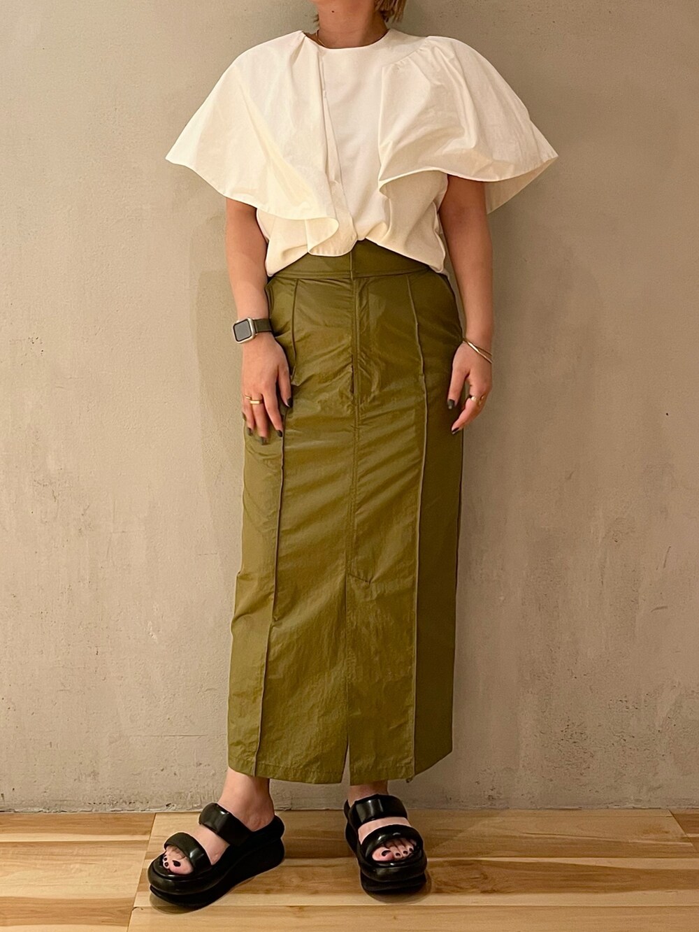 ホワイト系のTシャツ/カットソー、グリーン系のスカート、ブラック系のサンダルを着用したレディースの春コーディネートの4枚目の写真