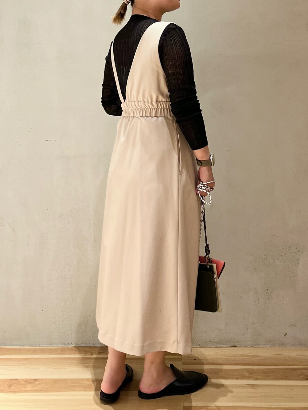 ベージュ系のショルダーバッグ、ベージュ系のジャンパースカート、ブラック系のニット/セーターを着用したレディースの冬コーディネートの2枚目の写真