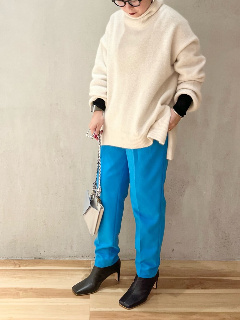 ブラック系のブーツ、ブラック系のTシャツ/カットソー、ホワイト系のニット/セーターを着用したレディースの冬コーディネートの4枚目の写真