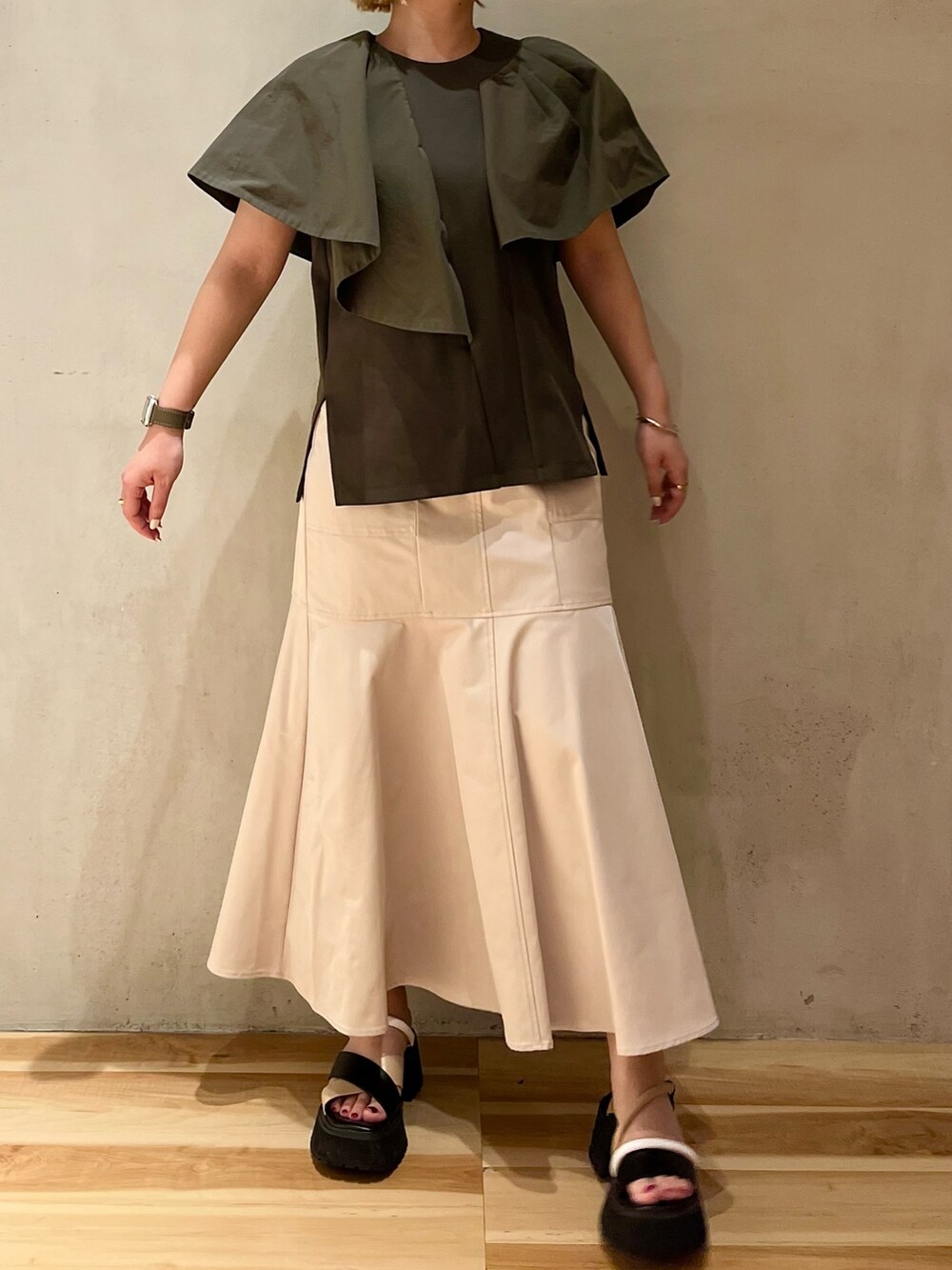 グリーン系のTシャツ/カットソー、ベージュ系のスカート、その他のサンダルを着用したレディースの春コーディネートの3枚目の写真