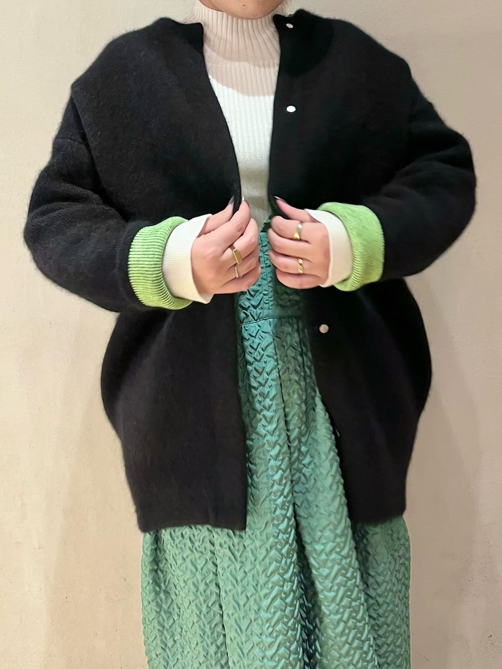ブラック系のノーカラージャケット、グリーン系のジャンパースカート、ホワイト系のニット/セーターを着用したレディースの秋コーディネートの4枚目の写真