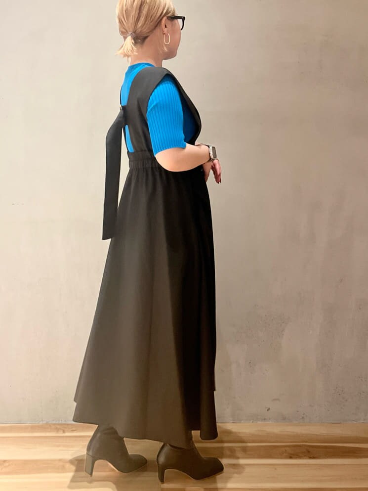 ブルー系のニット/セーター、ブラック系のジャンパースカート、ブラック系のブーツを着用したレディースの夏コーディネートの2枚目の写真