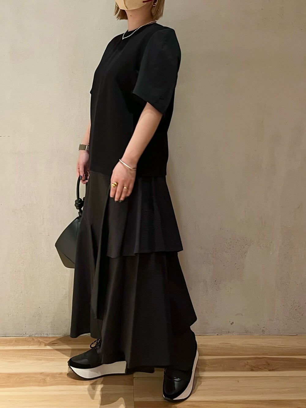 ブラック系のTシャツ/カットソー、ブラック系のスカート、ブラック系のハンドバッグを着用したレディースの春コーディネートの2枚目の写真